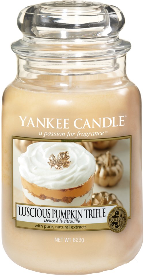 En krukke med Yankee Candle duftlys med gresskar og vanilje design, merket 'Luscious Pumpkin Trifle,' i klart glass.