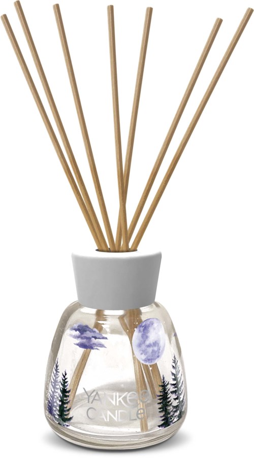 Ein Glasdiffusor mit Holzstäbchen und einer Naturmotive-Etikett mit Bäumen und Bergen.