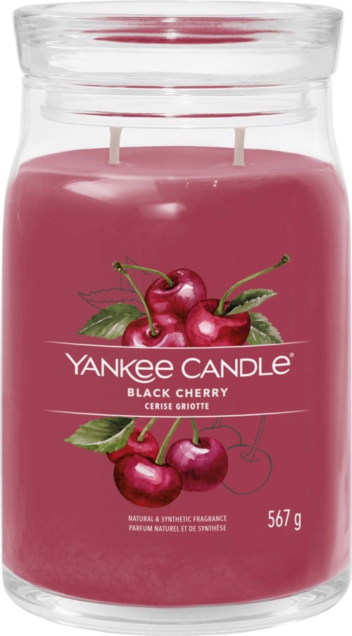 Et rosa lys i en klar glasskrukke med kirsebærillustrasjoner og merkevaren Yankee Candle på etiketten.