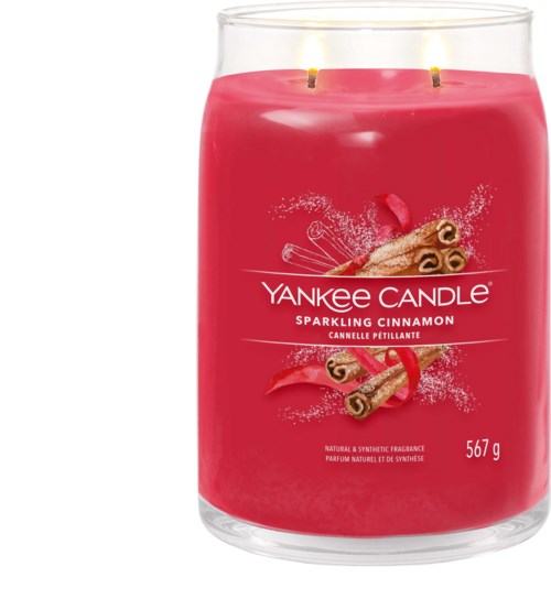 A pink candle labeled 'Yankee Candle Sparkling Cinnamon' with two lit wicks and cinnamon sticks on the label.