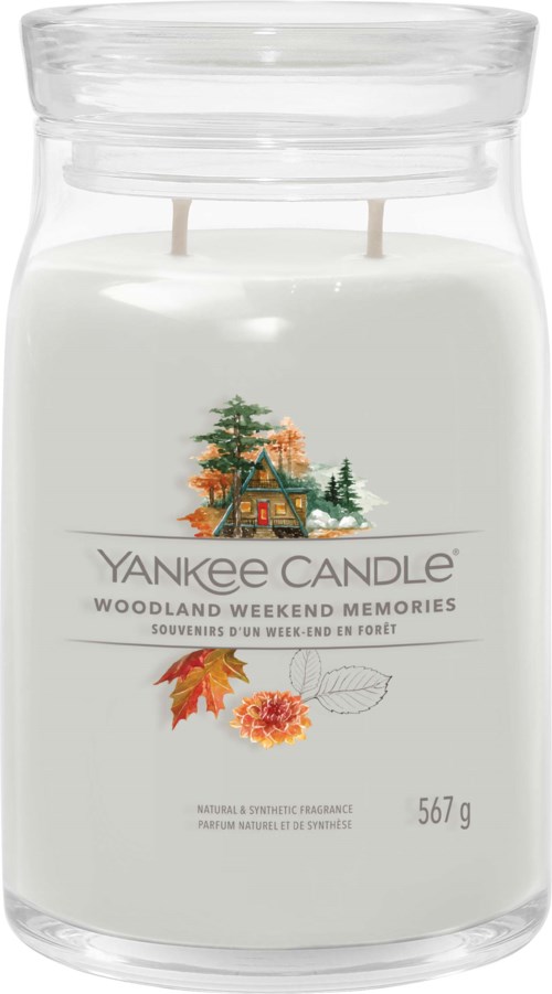 En vit ljus i glas med skogsscen, höstlöv och en blomma. Märket är Yankee Candle, skogslukt.