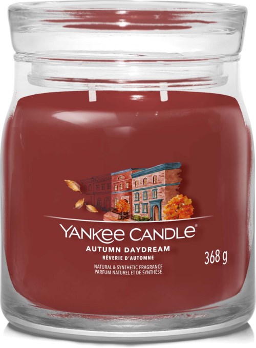 Czerwony słoik Yankee Candle z napisem 'Autumn Daydream' i obrazem budynku oraz jesiennych liści.