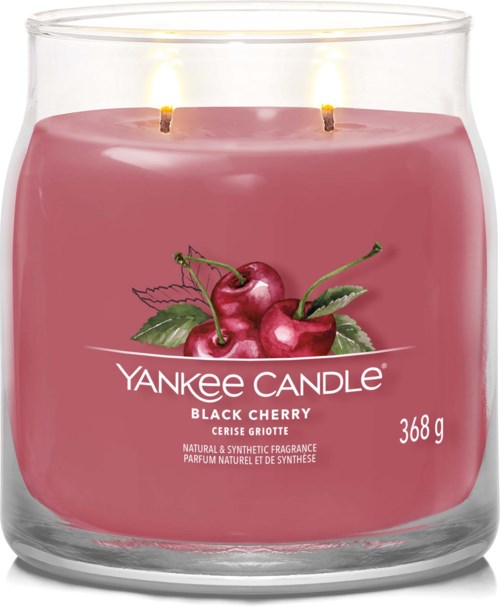 Rødt duftlys med kirsebær og grønne blader, etiketten sier Yankee Candle Black Cherry, 368g, har to flammer.