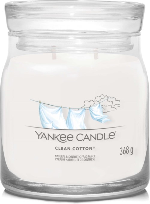 Ett tydligt candleljus i glasburk med etikett, som visar blå kläder som hänger tvätt utomhus och text om ljuset.