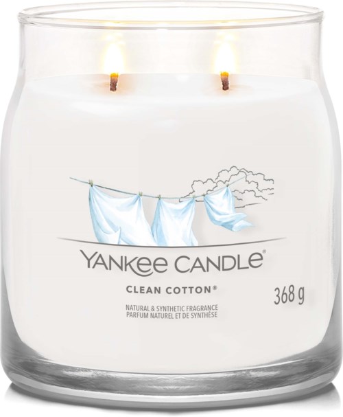 Ett doftljus med en tvättlina av bomullsmaterial och två tända vaxstickor, märkt 'Yankee Candle Clean Cotton,' 368 gram.