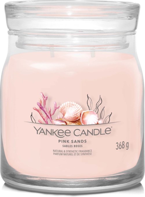 Ein kleiner rosa Duftkerze mit Muscheln und Korallen in einem klaren Glasbehälter.