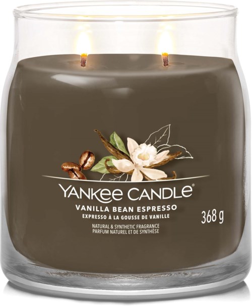 En mörkfärgad Yankee Candle med vita blommor och kaffebönor på etiketten, två tända vaxstickor och 368g vikt.
