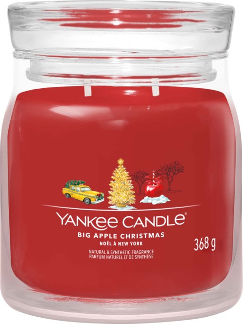 Ett rött doftljus med en julscen, inklusive ett julgran, en snögubbe och en gul bil, i ett glasskydd.