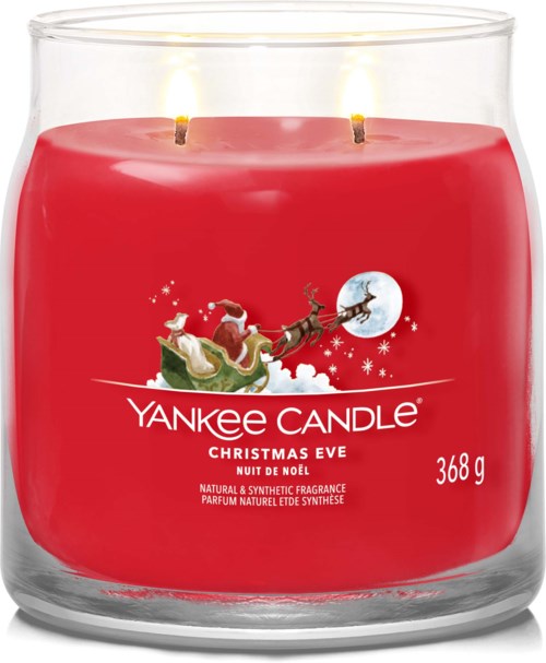 En rød duftlys i glass beholder har en scene med nissen, reinsdyr og fullmåne, merket 'Yankee Candle Christmas Eve.'