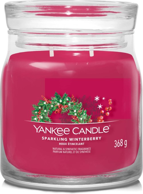 A pink Yankee Candle jar with a green holiday wreath design and white text about the winterberry scent.
