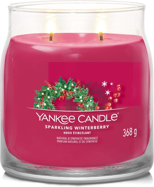 A pink candle with a holiday wreath and berries design, labeled "Yankee Candle Sparkling Winterberry," inside a clear glass container.