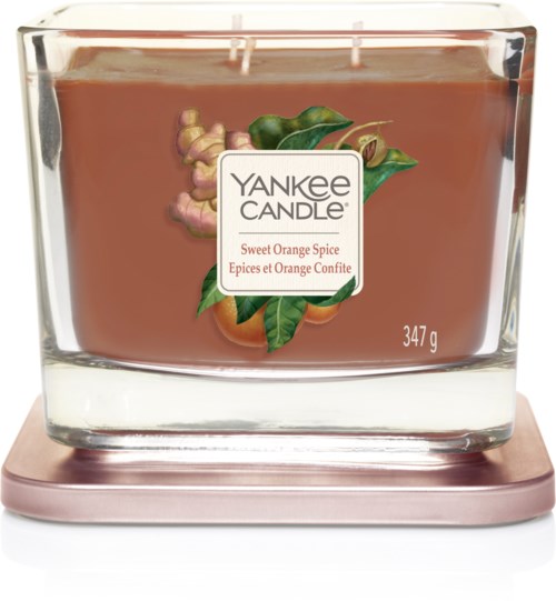 Duży świeca w szklanym pojemniku, oznaczona 'Yankee Candle,' z obrazami pomarańczy, liści i imbiru, waży 347 g.