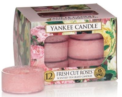 Förpackning med 12 rosa doftande tesljus med blommiga förpackningar och fönsterutställning.