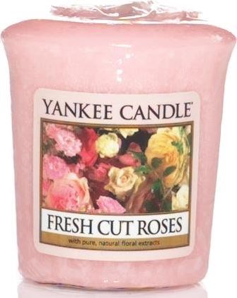 En rosa ljuslykta med etikett med färgglada rosor och orden "Yankee Candle Fresh Cut Roses."