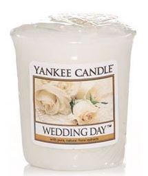 Biała świeca z etykietą "Yankee Candle Wedding Day" i róże na niej.