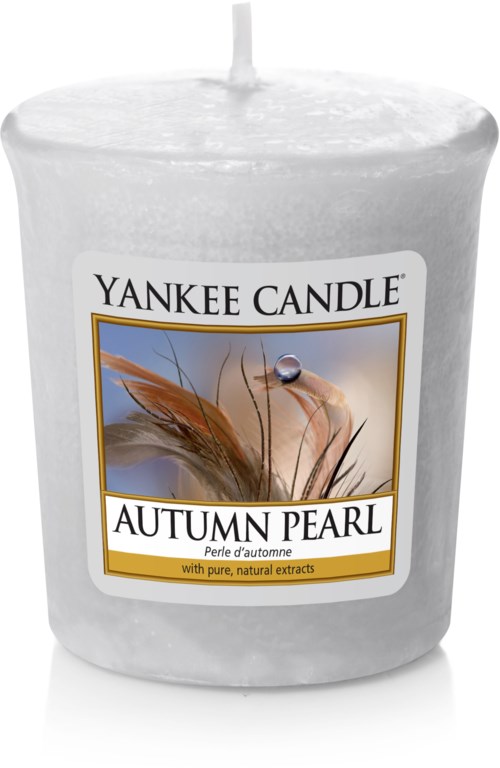 En vit ljuslykta med en etikett som visar en fjäder och en pärla, märkt 'Yankee Candle Autumn Pearl'.