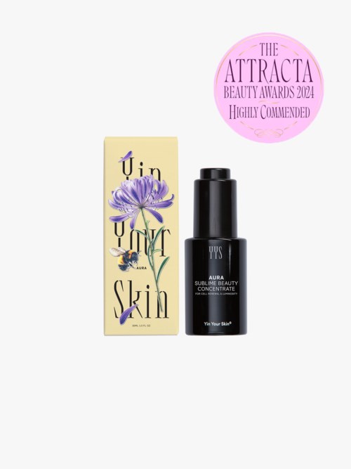 A skincare product in a black bottle with a matching box, featuring purple flowers and award recognition sticker.
