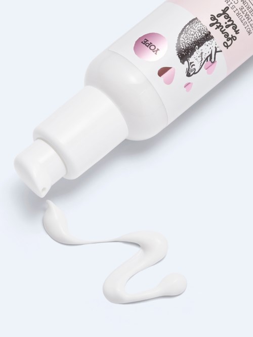 A white bottle with a pink label and a cartoon dog, with cream spilling from the opening.