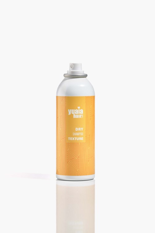 Eine weiße Sprühflasche mit orangefarbenem Etikett, auf dem 'Yuaia Texture Dry Shampoo' steht.