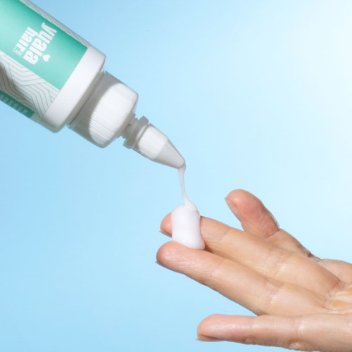 A hand applies hand sanitizer foam from a bottle onto fingers for cleaning.
