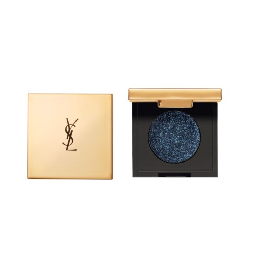 En gullfarget kosmetikkboks med blå glitterøyenskygge inni, og YSL-logo på lokket.