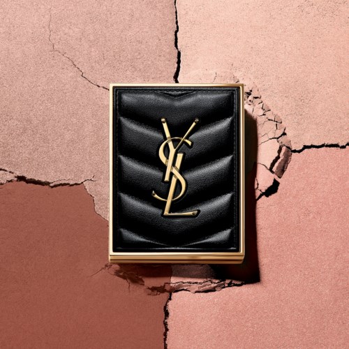 Yves Saint Laurent-logo i sort velouræske på en sprukket lyserød og brun vægbaggrund.