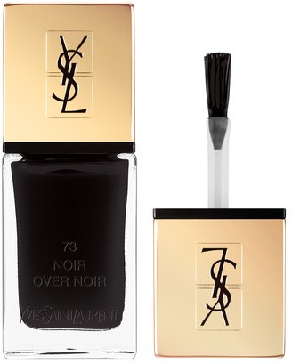 En svart neglelakkflaske med gullhette, YSL-logo og en svart pensel.
