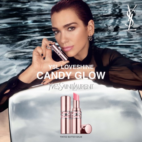Een vrouw houdt een lippenstift dicht bij haar gezicht met water op de achtergrond. Advertentie voor Yves Saint Laurent make-up.