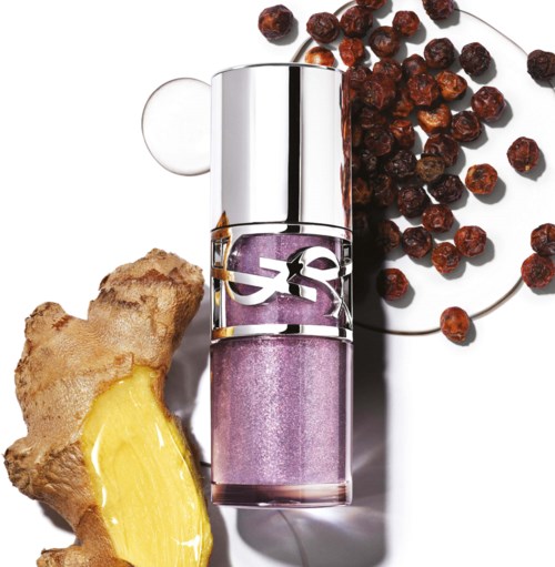 Een lippenstiftverpakking met paarse lippenstift, gember en kleine rode bessen op een witte achtergrond.