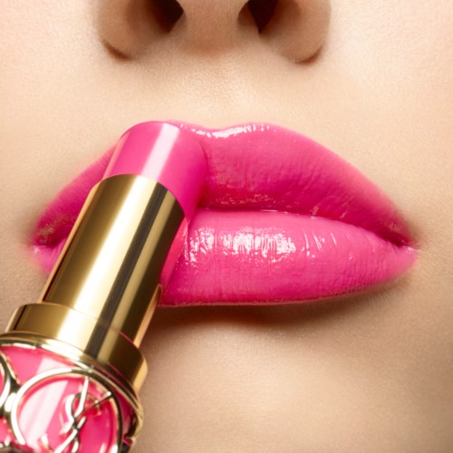 Close-up van lippen die roze lippenstift krijgen. De lippenstift is goudkleurig en glanzend. De lippen zijn nat en opvallend.