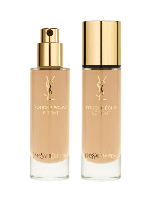 Två flaskor av Yves Saint Laurent Touché Éclat Le Teint foundation, en med spraylock och en med guldkork.