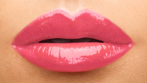 Nærbilde av lepper med glossy rosa leppestift, delvis åpne og viser en liten del av tennene.