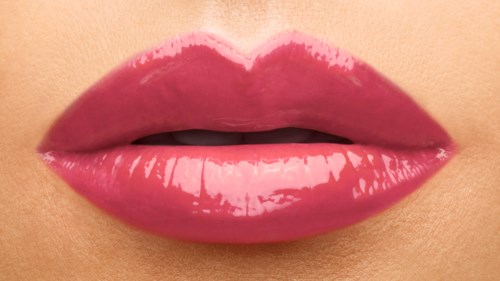 Nærbilde av glossy rosa lepper som er lett atskilt, viser litt tunge og tenner.
