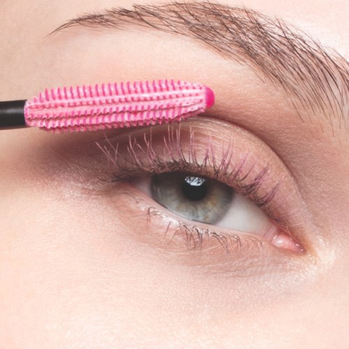 Persoon brengt roze mascara aan op onderwimpers met een wimperkrul.