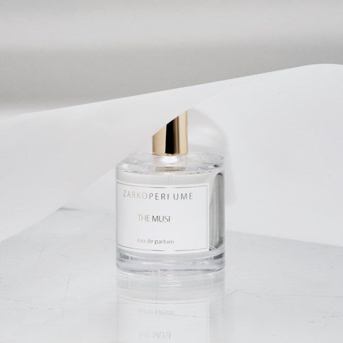 Eine klare Parfümflasche mit goldener Kappe, beschriftet 'ZARKO PERFUME THE MUSI' auf weißem Hintergrund.