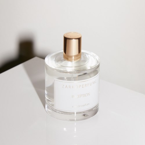 En klar parfymeflaske med gullkork på en hvit overflate; etiketten sier 'ZARKOPERFUME INCEPTION' og 'eau de parfum'.