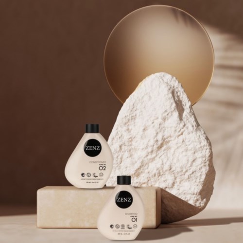 Två vita flaskor märka ZENZ, placerade på en beige block, med en stor vit sten och en rund guldfärgad spegel bakom.