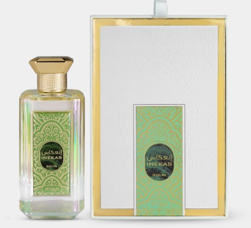 A perfume bottle and box with decorative green and gold designs, labeled 'INEKAS SOLID' in Arabic and English.