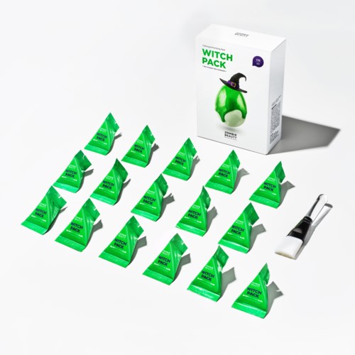Små grønne pakker merket 'Witch Pack' arrangert i rader, med en boks og en børste i nærheten.