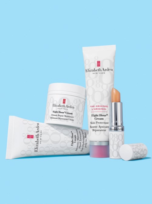 Hudvårdsprodukter med vit förpackning och rosa detaljer från Elizabeth Arden mot en blå bakgrund.