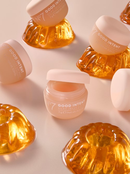 Små burkar med rosa lockar och orange geléliknande godsaker, placerade på en vit yta.