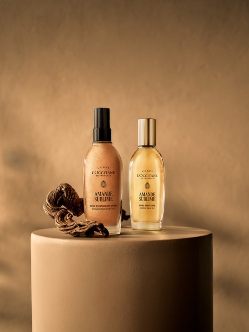Två flaskor av L'Occitane doft står på en rund yta, en med spraylock och en hårklämma bredvid.
