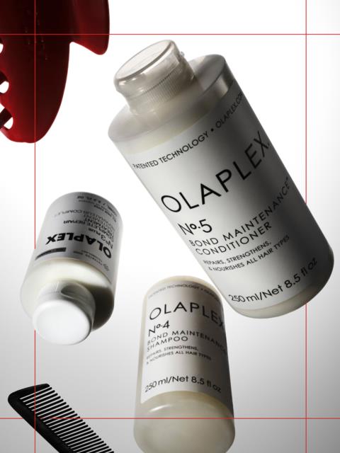 Three bottles of Olaplex hair care products are displayed, including shampoo and conditioner, with a comb nearby.
