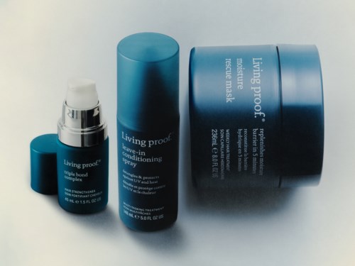 Tre blå hudvårdsförpackningar märkta Living Proof visas, inklusive ett leave-in balsam, spray och en större mask.
