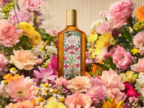En Gucci Flora-parfymflaska omgiven av färgglada blommor som rosa, gula och vita blommor.