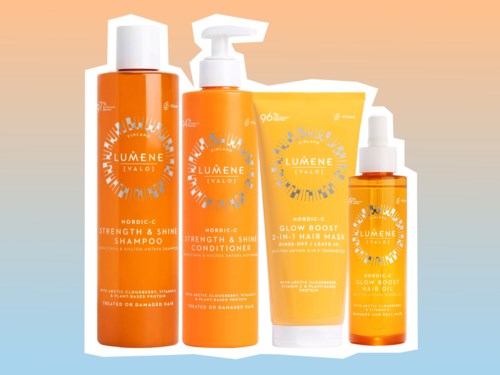 Sæt med fire orange hårplejeprodukter inklusive shampoo, balsam, leave-in gel og spray med hvide låse og etiketter.