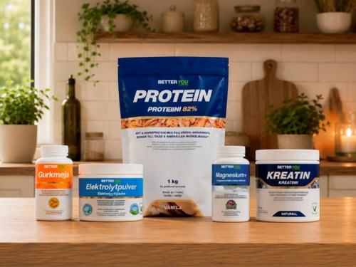 Ett urval av fitness- och kosttillskott inklusive proteinpulver, magnesium, proteinfett, ett multivitamin och kreatin på ett träbänkskivor i ett mysigt kök.