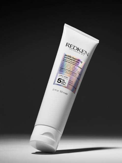 Vit tub med Redken Acidic Bonding Concentrate hårvårdsprodukt mot mörk bakgrund.