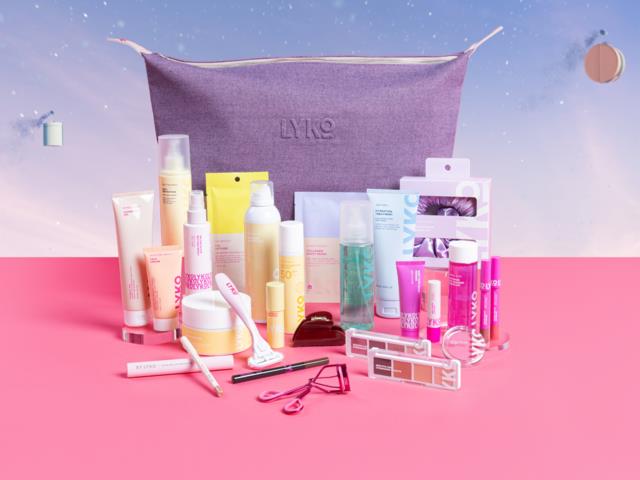 Various skincare, makeup, and beauty products arranged in front of a purple Lyko bag on a pink and blue background.