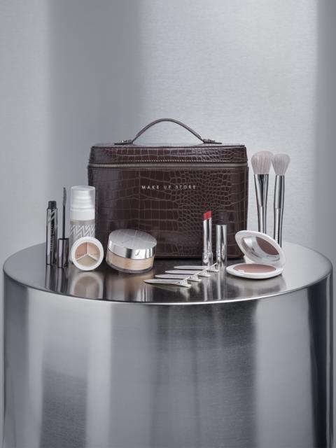 Makeup-kit med borstar, läppstift, rouge och hudvårdsprodukter på ett silverbord.